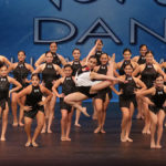 Large dance group performing on stage at CRU Dance Nationals